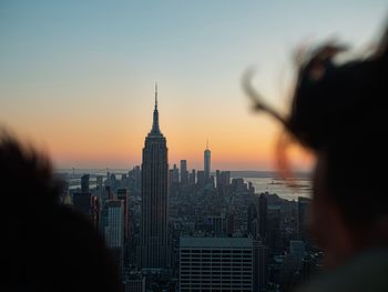 A couple view the empire state building from the rockefeller center rooftop
