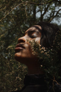 Close-up portrait of young woman looking away in forest