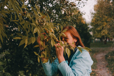 Midsection of woman with leaves against trees