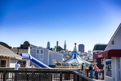 People in amusement park against blue sky