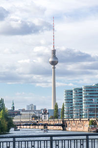 Communications tower in city against sky
