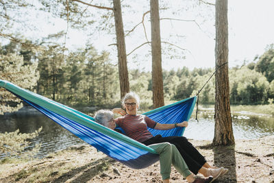 Two senior women resting in hammock at lakeshore