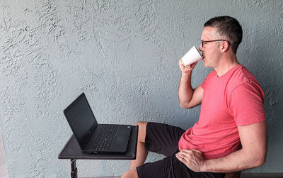 Business professional working from home at laptop drinking coffee in mockups.