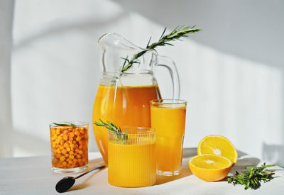Raw sea buckthorn and orange juice in glasses. with rosemary. antioxidant drink for immunity boost 