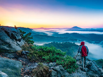 Travel landscape photographer with digital camera making photo of morning misty country