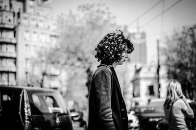 Rear view of woman standing against sky in city