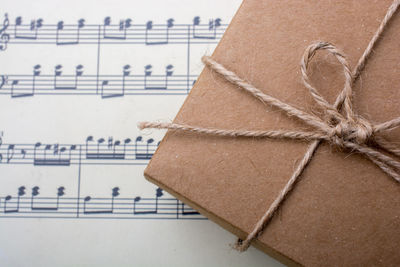 Close-up of rope tied to box on sheet music
