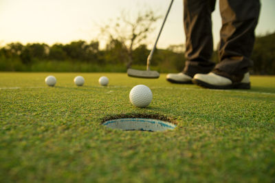 Surface level of man hitting bole in hole at golf course