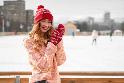 Portrait of smiling young woman wearing knit hat standing outdoors