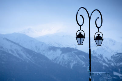 Street light and snowcapped mountains against sky