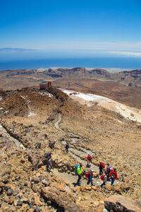 High angle view of tourist walking over hill against cloudy sky