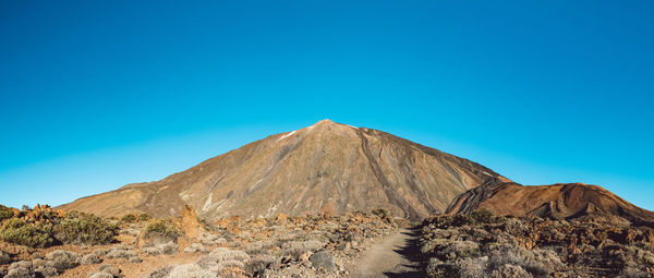 Scenic view of volcanic mountain against clear blue sky