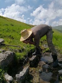 Full length of man drinking water on field against sky