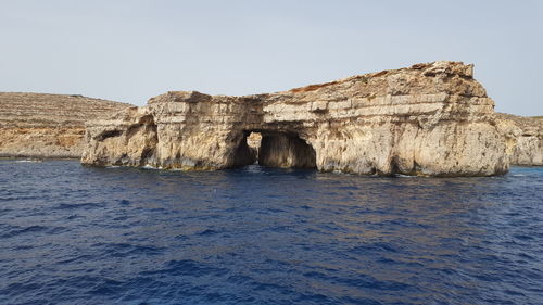 Rock formations in sea against clear sky