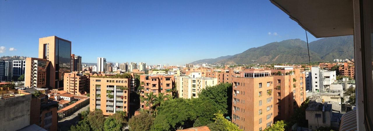 building exterior, architecture, built structure, clear sky, city, residential district, cityscape, mountain, residential structure, residential building, house, blue, crowded, high angle view, tree, town, copy space, sunlight, sky, city life