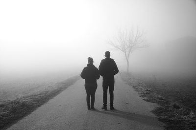 Rear view of couple standing on road against sky
