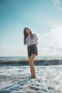 Full length of young woman standing on beach