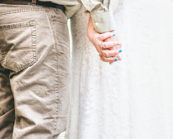 Midsection of bride and bridegroom holding hands during wedding ceremony