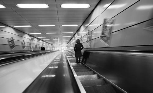 Rear view of woman walking on illuminated subway station