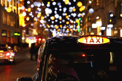 Man driving taxi on illuminated street