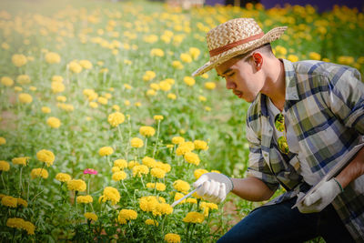 Midsection of person with yellow flowers in field