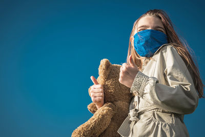 Low angle view of woman against blue sky