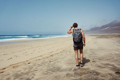 Rear view of man walking at beach