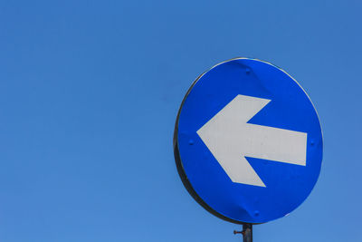 Low angle view of road sign against clear blue sky