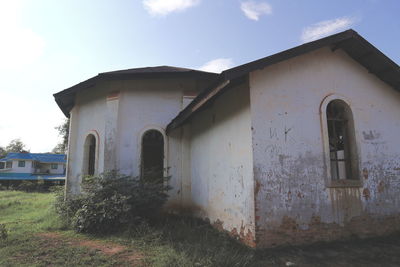 Exterior of old house on field against sky