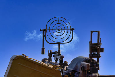 Low angle view of machine part against blue sky