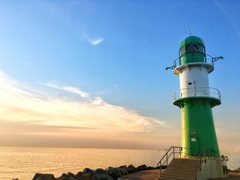 Lighthouse by sea against sky