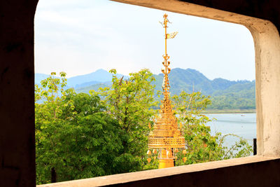 Temple against trees and mountains against sky