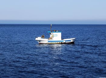 Boat sailing in sea against clear sky