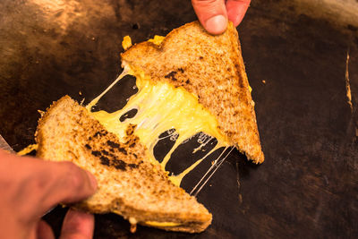 Close-up of hands holding cheese sandwich