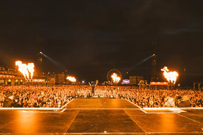 People at illuminated street against sky at night