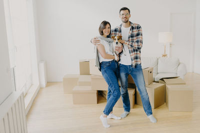 Portrait of couple with dog standing in new home