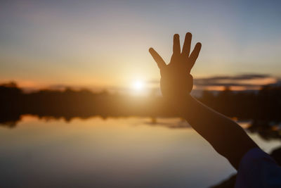 Low angle view of silhouette hand against sky during sunset