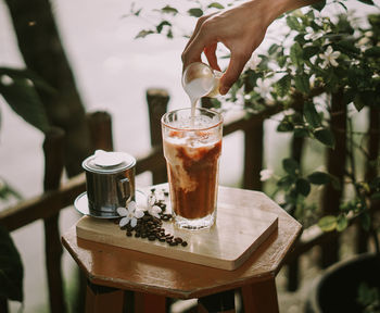 Close-up of hand holding drink on table