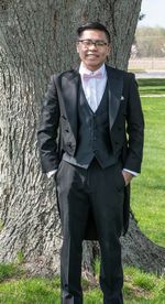 Portrait of man standing by tree trunk