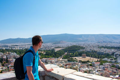 Side view of man standing on mountain against clear sky