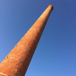 Low angle view of smoke stack against clear blue sky