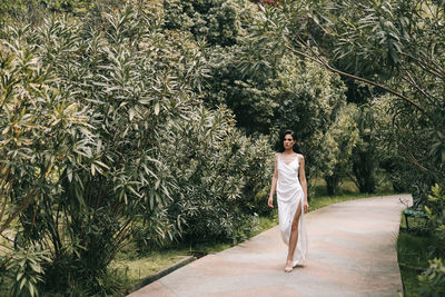 Woman standing by tree against plants