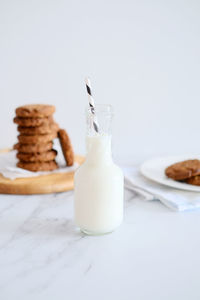 Glass jar of milk with a straw with homemade cookies on the background