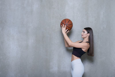 Full length of woman on playing with ball standing by wall