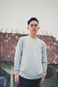 Portrait of young man standing against clear sky