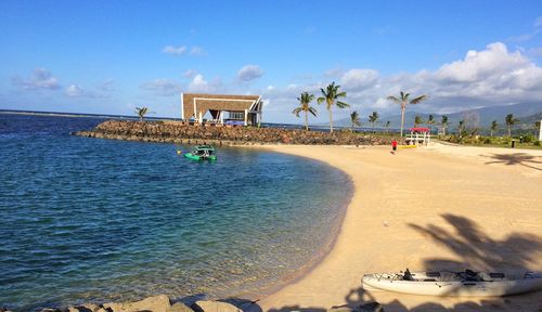 People by swimming pool at beach against sky