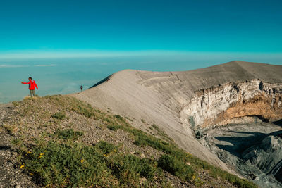 Rear view of man standing on mountain against sky