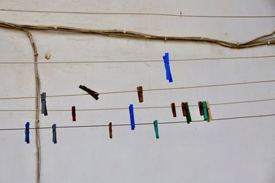 Low angle view of clothespins hanging against white wall