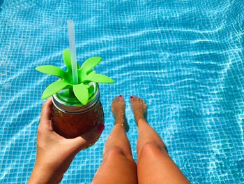 Low section of woman with drink in swimming pool