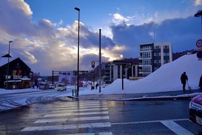 City street by buildings against sky during winter